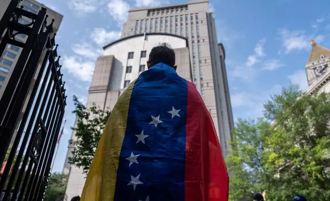 A Venezuelan man, who is in opposition to former Venezuela President Nicolas Maduro and his wife Cilia Flores, wears a Venezuelan flag, before they appear at Manhattan federal court, Wednesday, July 22, 2026, in New York.(AP Photo/Adam Gray)