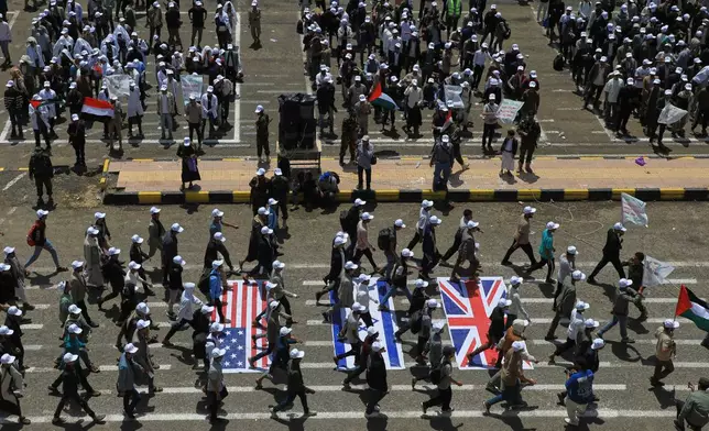 Demonstrators march over depictions of the flags of the United States, Israel and the United Kingdom during a rally against the Saudi-led coalition in Sanaa, Yemen, Wednesday, July 22, 2026. (AP Photo/Osamah Abdulrahman)
