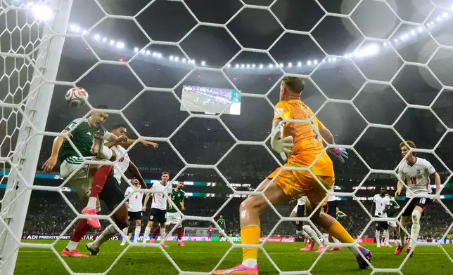 Mexico's Cesar Montes, left, and England's Jude Bellingham (10) battle for the ball in front of England goalkeeper Jordan Pickford (1) during the World Cup round of 16 soccer match between Mexico and England in Mexico City, Sunday, July 5, 2026. (AP Photo/Ricardo Mazalan )