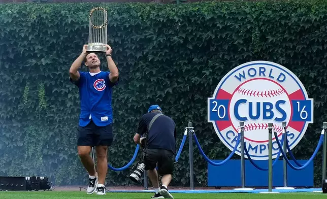 Former Chicago Cubs first baseman Anthony Rizzo holds up the 2016 World Series Championship trophy as his walks on the field before a baseball game between the Minnesota Twins and the Chicago Cubs in Chicago, Saturday, July 18, 2026. (AP Photo/Nam Y. Huh)