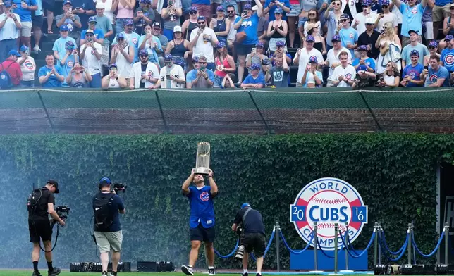 Former Chicago Cubs first baseman Anthony Rizzo holds up the 2016 World Series Championship trophy as his walks on the field before a baseball game between the Minnesota Twins and the Chicago Cubs in Chicago, Saturday, July 18, 2026. (AP Photo/Nam Y. Huh)