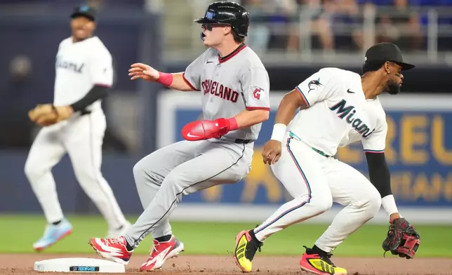 Cleveland Guardians' Travis Bazzana, center, advances to second base on a base hit as Miami Marlins shortstop Otto Lopez, right, tries to field the ball during the first inning of a baseball game, Saturday, July 11, 2026, in Miami. (AP Photo/Jim Rassol)