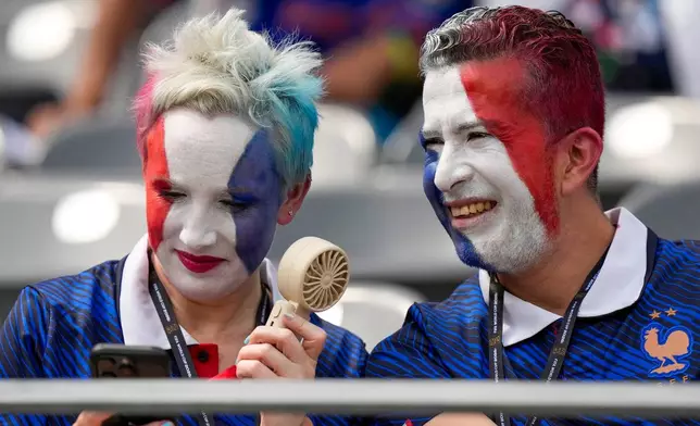 France supporters cool down with a fan before the World Cup round of 32 soccer match between France and Sweden in East Rutherford, N.J., near New York, Tuesday, June 30, 2026. (AP Photo/Frank Franklin II)