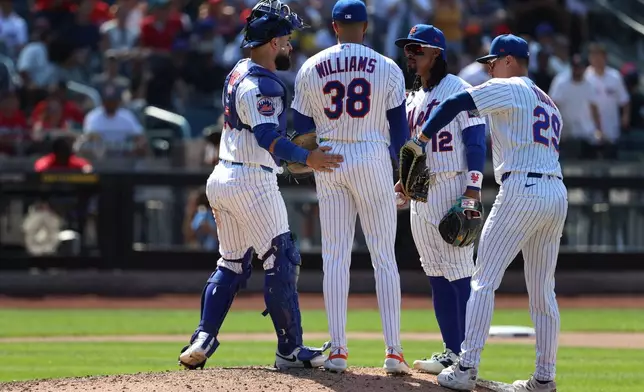 New York Mets players visit pitcher Devin Williams (38) on the mound during the ninth inning of a baseball game against the Boston Red Sox, Sunday, July 12, 2026, in New York. (AP Photo/Pamela Smith)