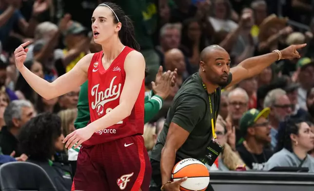 Indiana Fever guard Caitlin Clark points for possession as former Seattle Seahawks wide receiver Doug Baldwin, right, picks up the ball and calls for Seattle Storm possession during the first half of a WNBA basketball game, Tuesday, July 28, 2026, in Seattle. (AP Photo/Lindsey Wasson)