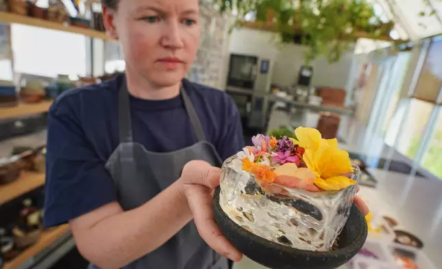 Noma's head of R&D Mette Brink Soberg holds a new berry gazpacho dish topped with flower petals in fine-dining restaurant Noma's test kitchen in Copenhagen, Denmark Tuesday, July 28, 2026. (AP Photo/James Brooks)