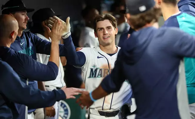 Seattle Mariners' Cole Young (2) celebrates with teammates in the dugout after scoring on a single hit by Victor Robles in the seventh inning of a baseball game against the Los Angeles Angels, Tuesday, June 30, 2026, in Seattle. (AP Photo/Kevin Ng)