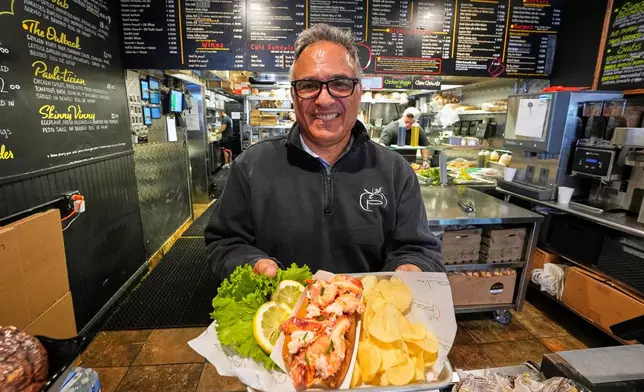 Principal Paul Barker serves lobster rolls to World Cup tourists at Pauli's sandwich shop in the North End of Boston, Wednesday, June 24, 2026. (AP Photo/Martin Meissner)