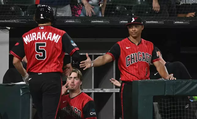 Chicago White Sox's Munnetaka Murakami (5) celebrates with manager Will Venable, right, at the dugout after scoring on a Miguel Vargus double during the seventh inning of a baseball game against The Athletics in Chicago, Friday, July 10, 2026. (AP Photo/Paul Beaty)