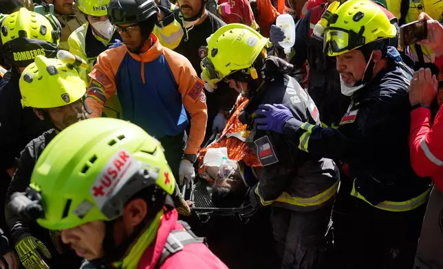 Rescue workers carry Hernán Alberto Gil Flores Gil after he was pulled from the rubble eight days after he was trapped by twin earthquakes that struck Catia La Mar, Venezuela, Thursday, July 2, 2026. (AP Photo/Fernando Vergara)