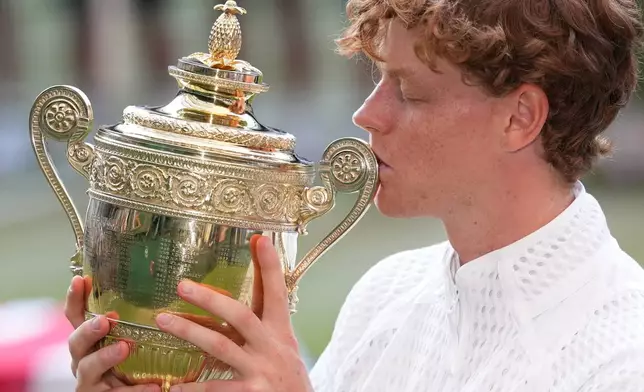 Jannik Sinner of Italy kisses his trophy after winning against Alexander Zverev of Germany in the men's singles final at Wimbledon Tennis Championships in London, Sunday, July 12, 2026. (AP Photo/Kirsty Wigglesworth)