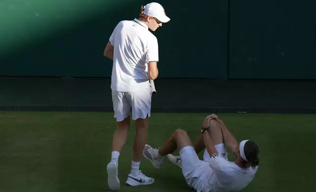 Jannik Sinner of Italy helps Alexander Zverev of Germany get up after falling over during a point in their men's singles final at Wimbledon Tennis Championships in London, Sunday, July 12, 2026. (AP Photo/Brian Inganga)