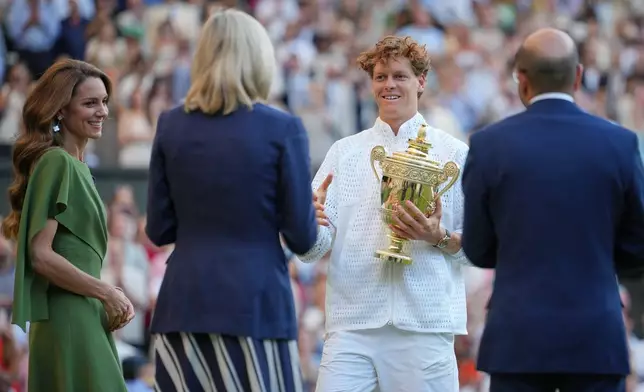 Jannik Sinner of Italy holds the winner trophy after defeating Alexander Zverev of Germany, as tKaye Princess off Wales looks on, left, in the men's singles final at Wimbledon Tennis Championships in London, Sunday, July 12, 2026. (AP Photo/Kin Cheung)