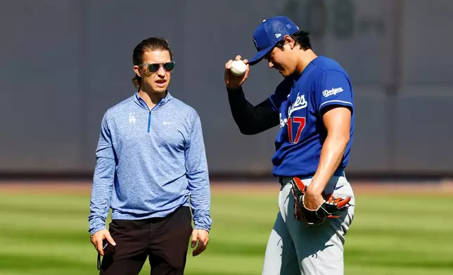 Los Angeles Dodgers' Shohei Ohtani, right, stands in the outfield with trainer Albert Thomas, left, before the second game of a baseball doubleheader against the New York Yankees, Sunday, July 19, 2026, in New York. (AP Photo/Noah K. Murray)