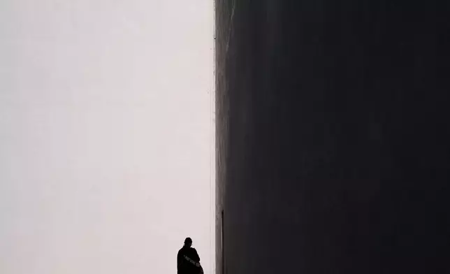 A woman is silhouetted against the sunlit facade of a building as she walks toward an entrance in Costa Mesa, Calif., Friday, July 17, 2026. (AP Photo/Jae C. Hong)
