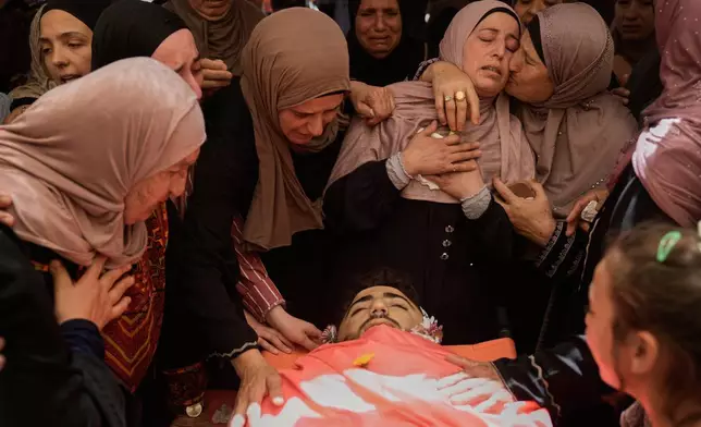 Mourners take a last look at the body of Palestinian Fadi Na'asan, 17, who succumbed to his wounds sustained during clashes with Israeli army soldiers last Saturday, during his funeral in the West Bank village of al-Mughayyir, Saturday, July 18, 2026. (AP Photo/Majdi Mohammed)
