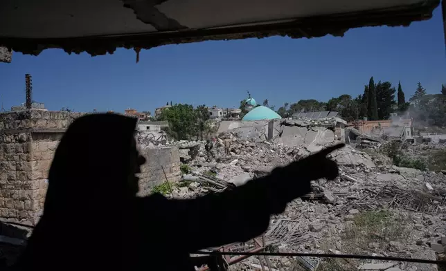Mahasen Faqih gestures toward the rubble of her neighborhood from inside her destroyed home after returning to it following the Israeli military operation in Zawtar al-Gharbieh, Lebanon, Tuesday, July 28, 2026. (AP Photo/Hassan Ammar)