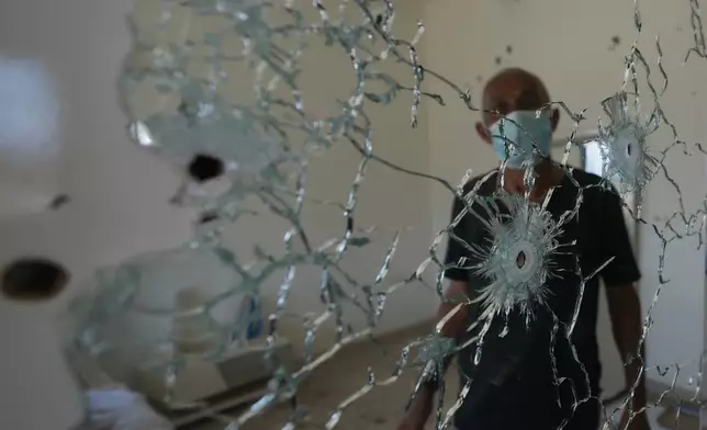 A resident stands behind a mirror riddled with bullet holes inside his home following an Israeli military operation in Zawtar al-Gharbieh, Lebanon, Tuesday, July 28, 2026. (AP Photo/Hassan Ammar)