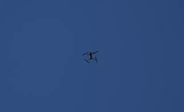 An Israeli drone flies overhead as journalists, Lebanese soldiers and residents gather in Zawtar al-Gharbieh, Lebanon, Tuesday, July 28, 2026. (AP Photo/Hassan Ammar)