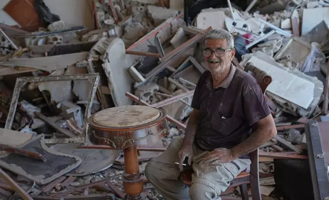 Mohammed Sobeih laughs as he smokes a cigarette while sitting amid the rubble of his home after returning to it following the Israeli military operation in Zawtar al-Gharbieh, Lebanon, Tuesday, July 28, 2026. (AP Photo/Hassan Ammar)