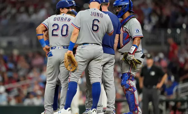 The Texas Rangers speak with pitcher Emiliano Teodo on the mound in the fifth inning of a baseball game against the Atlanta Braves, Friday, July 17, 2026, in Atlanta. (AP Photo/Mike Stewart)