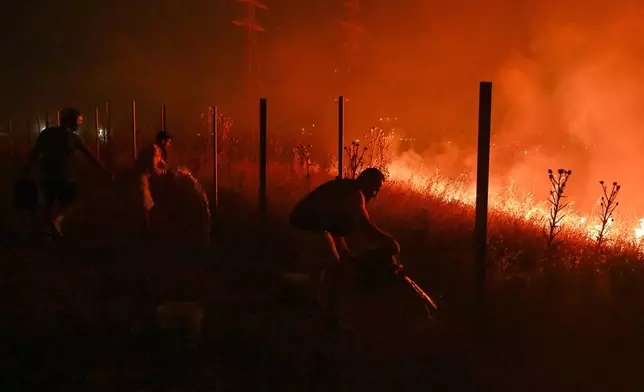 Locals try to extinguish a wildfire on the outskirts of the northern city of Thessaloniki, Greece, Saturday, July 4, 2026. (AP Photo/Giannis Papanikos)