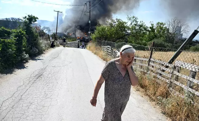 A woman reacts during a wildfire on the outskirts of the northern city of Thessaloniki, Greece, Sunday, July 5, 2026. (AP Photo/Giannis Papanikos)