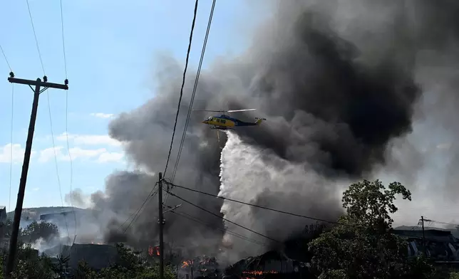A helicopter drops water over a wildfire on the outskirts of the northern city of Thessaloniki, Greece, Sunday, July 5, 2026. (AP Photo/Giannis Papanikos)