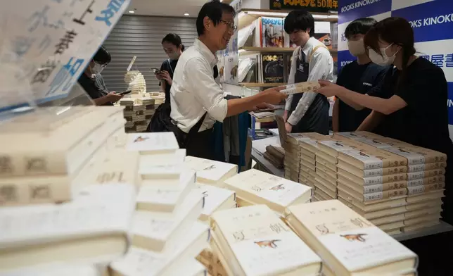 A man receives a copy of Haruki Murakami's new book titled "The Tale of KAHO" minutes after the clock struck midnight at a Kinokuniya bookstore in Tokyo, Friday, July 3, 2026. (AP Photo/Hiro Komae)
