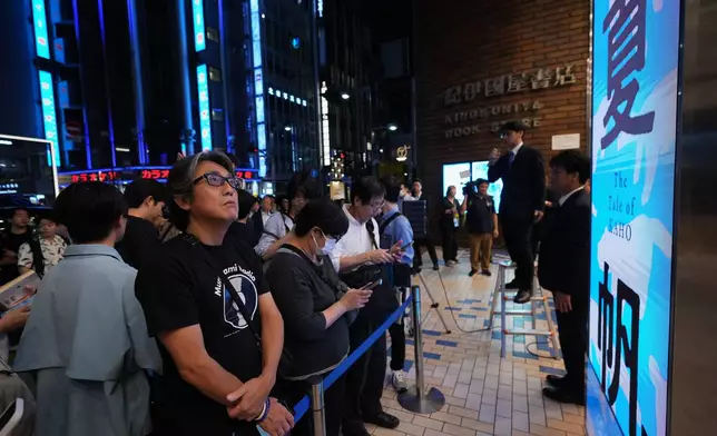 People attend a countdown event to receive copies they pre-purchased, of Haruki Murakami's new book, titled "The Tale of KAHO" after the clock strikes midnight, at a Kinokuniya bookstore in Tokyo on Thursday, July 2, 2026. (AP Photo/Hiro Komae)