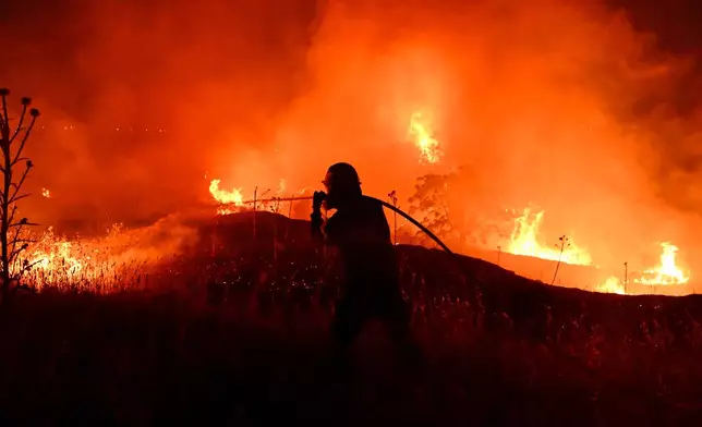 A firefighter works on a wildfire on the outskirts of the northern city of Thessaloniki, Greece, Saturday, July 4, 2026. (AP Photo/Giannis Papanikos)