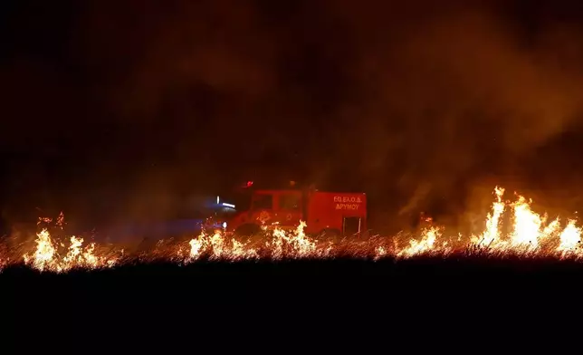 A firefighting vehicle drives near wildfires on the outskirts of the northern city of Thessaloniki, Greece, Saturday, July 4, 2026. (AP Photo/Giannis Papanikos)