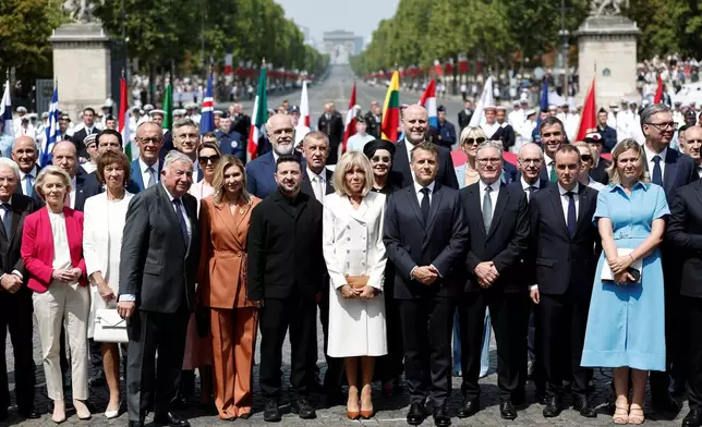 French President Emmanuel Macron, his wife Brigitte Macron, Ukraine's President Volodymyr Zelenskyy and his wife Olena Zelenska, Heads of State and Government of the Coalition of the Willing, President of the National Assembly Yael Braun-Pivet, and President of the Senate Gerard Larcher pose for a family photo after the annual Bastille Day military parade on the Place de la Concorde in Paris, France, Tuesday, July 14, 2026. (Benoit Tessier/Pool photo via AP)