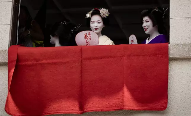 A geiko, a regional word for geisha, and a maiko watch one of the main parades of Shinto's Gion Matsuri festival in Kyoto, western Japan, Friday, July 17, 2026. (AP Photo/Fred Mery)