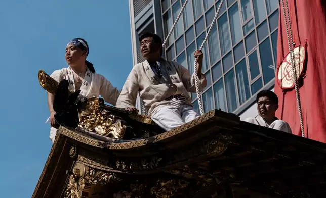 Festivalgoers are seen atop a festival float during one of the main parades of Shinto's Gion Matsuri festival in Kyoto, western Japan, Friday, July 17, 2026. (AP Photo/Fred Mery)