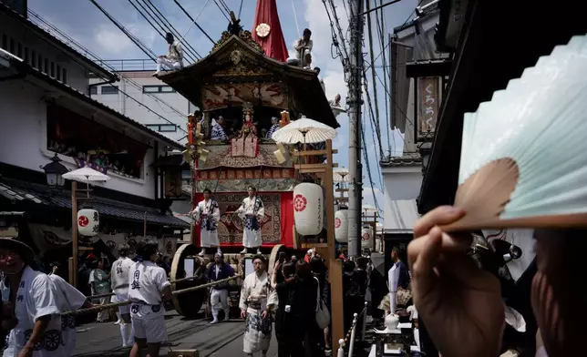 A festival float passes through a narrow street during one of the main parades of Shinto's Gion Matsuri festival in Kyoto, western Japan, Friday, July 17, 2026. (AP Photo/Fred Mery)