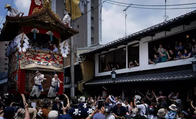 A giant festival float is paraded through a cheering crowd during one of the main parades of Shinto's Gion Matsuri festival in Kyoto, western Japan, Friday, July 17, 2026. (AP Photo/Fred Mery)