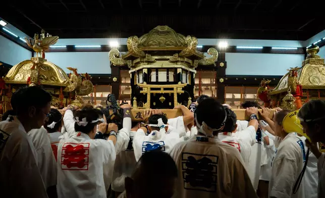Festival participants carry Yasaka Shrine's Eastern Mikoshi back into the shrine's main hall following the "Mikoshi Arai" purification ritual ahead of the Gion Matsuri festival in Kyoto, western Japan, Friday, July 10, 2026. (AP Photo/Fred Mery)