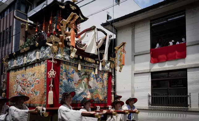 A festival float passes by maikos and geikos watching one of the main parades of Shinto's Gion Matsuri festival in Kyoto, western Japan, Friday, July 17, 2026. (AP Photo/Fred Mery)