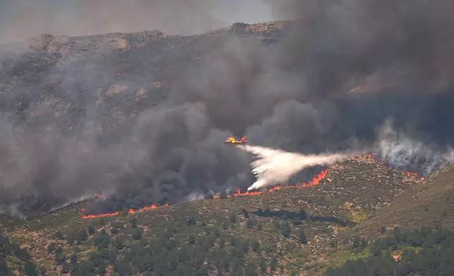 A seaplane drops water onto the fire as a wildfire advances near La Adrada, Ávila province, Spain, Friday, July 24, 2026. (AP Photo/Manu Fernandez)