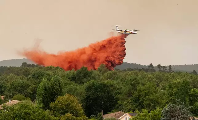 A water bomber drops water while fighting wildfires in the Lège-Cap-Ferret region, western France, Thursday, July 23, 2026. (AP Photo/Caroline Blumberg)