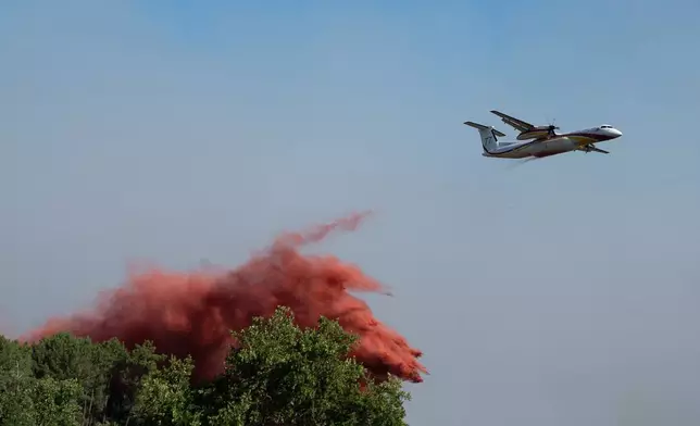 A water bomber drops water while fighting wildfires In Ares, western France, Friday July 24, 2026. (AP Photo/Caroline Blumberg)