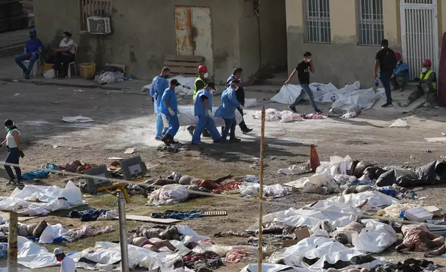 EDS NOTE: GRAPHIC CONTENT - Emergency workers gather the bodies of earthquake victims in the parking lot of a hospital three days after twin earthquakes struck, in La Guaira, Venezuela, Saturday, June 27, 2026. (AP Photo/Matias Delacroix)