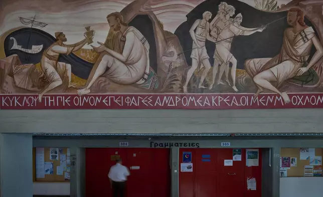 A man walks past a mural by George Kordis depicting Odysseus blinding the Cyclops Polyphemus at the School of Philosophy of the National and Kapodistrian University of Athens, Wednesday, May 20, 2026. (AP Photo/Petros Giannakouris)