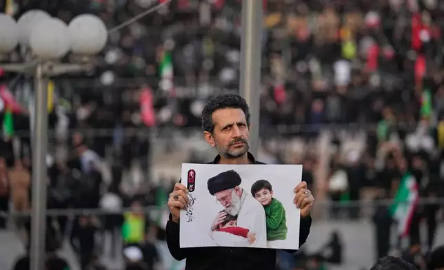 A man holds a picture of slain Iranian Supreme Leader Ayatollah Ali Khamenei as a crowd waits for his casket to arrive at the Imam Khomeini Mosalla Grand Mosque for the start of the dayslong funeral ceremonies in Tehran, Iran, Saturday, July 4, 2026. (AP Photo/Altaf Qadri)