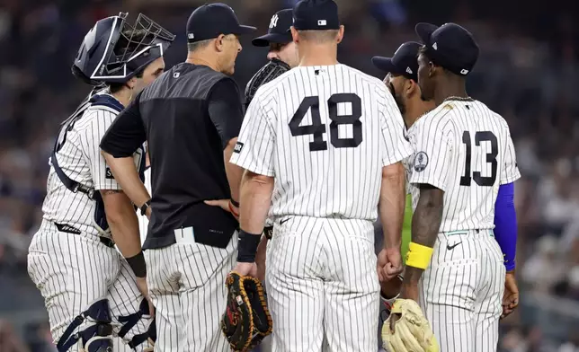 New York Yankees manager Aaron Boone, second left, confers with Gerrit Cole during the seventh inning of a baseball game against the Los Angeles Dodgers, Friday, July 17, 2026, in New York. (AP Photo/Adam Hunger)