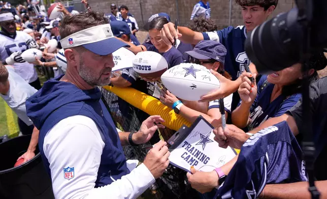 Dallas Cowboys head coach Brian Schottenheimer signs autographs during the NFL football team's training camp, Wednesday, July 29, 2026, in Oxnard, Calif. (AP Photo/Mark J. Terrill)