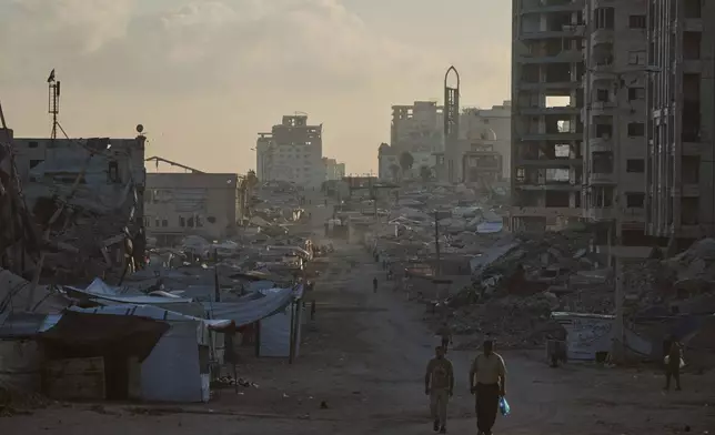 Palestinians walk along a street surrounded by buildings destroyed in Israeli military strikes during the Israel-Hamas war, in Gaza City, Thursday, July 2, 2026. (AP Photo/Jehad Alshrafi)