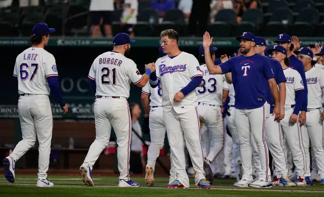 Texas Rangers' Jacob Latz (67), Jake Burger (21), Joc Pederson, center, Nathan Eovaldi, right and the rest of the team celebrate their win against the Seattle Mariners in a baseball game in Arlington, Texas, Monday, July 27, 2026. (AP Photo/Tony Gutierrez)