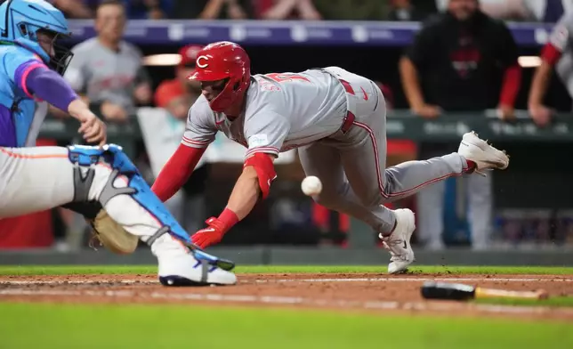 Colorado Rockies catcher Hunter Goodman, left, fields the throw as Cincinnati Reds' Spencer Steer slides safely into home plate to notch an inside-the-park home run off Colorado relief pitcher Jeff Criswell in the eighth inning of a baseball game Friday, July 17, 2026, in Denver. (AP Photo/David Zalubowski)